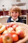 Молодий хлопчик сидить за обіднім столом з яблуками — стокове фото