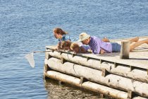 Family fishing with net on wooden pier — Stock Photo