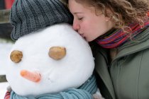 Женщина целует снеговика — стоковое фото