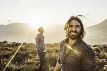 Man and friend on grassland looking at camera smiling — Stock Photo
