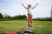 Хлопчик стрибає середнє повітря в полі — стокове фото