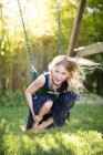 Retrato de menina agachado enquanto balançando no balanço do jardim — Fotografia de Stock