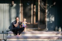 Uomo maturo seduto su gradini con giovane figlia, ritratto — Foto stock