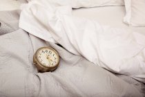 Alarm clock on bed — Stock Photo