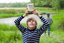 Boy looking at tadpoles in jar — Stock Photo