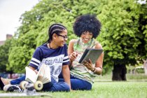 Junge und Mutter lesen digitales Tablet im Park — Stockfoto