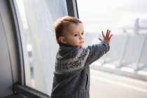 Boy tocando ventana del aeropuerto - foto de stock