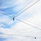 Low angle view of blue sky and street lights with criss crossed wires — Stock Photo