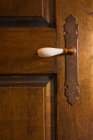 Close-up of a white porcelain door handle on an old wooden door in the master bedroom on the upstairs floor inside a 2003 built cottage style residential log home, Quebec, Canada. This image is property released. CUPR0244 — Stock Photo