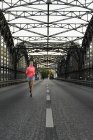Young female runner across bridge — Stock Photo