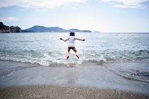 Маленький хлопчик стрибає в море — стокове фото