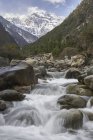 Acqua che scorre lungo il fiume dalle montagne innevate, Contea di Shangri-la, Yunnan, Cina — Foto stock
