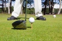 Pés de jogador de golfe e bola com clube de golfe em primeiro plano — Fotografia de Stock