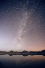 Reflecting pool of mountain range and Milky Way in night sky — Stock Photo