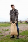 Boy carrying sack of feed — Stock Photo