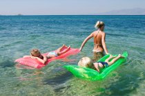 Mädchen und Junge auf aufblasbaren Matratzen im Meerwasser mit Mama — Stockfoto