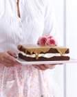 Женщина держит шоколадный бисквит кофе торт украшен цветами — стоковое фото