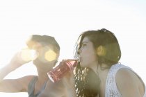 Young couple drinking soft drinks at beach — Stock Photo