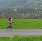 Young girl running along footpath — Stock Photo