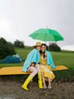 Zwei Frauen sitzen unter einem Regenschirm — Stockfoto