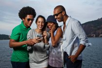 Чотири друзі дивляться на мобільний телефон — стокове фото