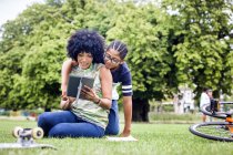 Хлопчик і мати читають цифровий планшет разом у парку — стокове фото