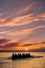 Huit personnes ramant au coucher du soleil — Photo de stock