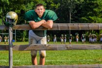 Retrato adolescente jugador de fútbol americano masculino con casco en el campo de juego - foto de stock