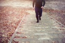 Mature man, outdoors, running up steps, cropped shot — Stock Photo