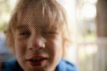 Молодий хлопчик дивиться через дверний екран — стокове фото