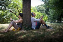 Junges Paar lehnt an Baumstamm — Stockfoto