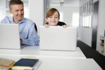 Padre e hijo usando computadoras portátiles - foto de stock