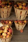 Wooden baskets of ripe peaches on shelves — Stock Photo