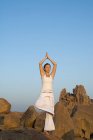 Mujer en yoga posan por rocas - foto de stock