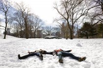Молодая пара, лежащая в снежном Центральном парке, Нью-Йорк, США — стоковое фото