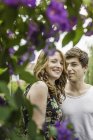 Portrait of young couple surrounded by foliage and flowers — Stock Photo