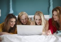 Cuatro chicas adolescentes mirando el portátil en el dormitorio - foto de stock
