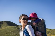 Mãe carregando a filha jovem nas costas, caminhando pela trilha da costa de Bonneville no sopé de Wasatch acima de Salt Lake City, Utah, EUA — Fotografia de Stock