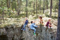 Дети, сидящие на скалах в лесу, едят пикник — стоковое фото
