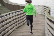 Donna che corre su una banchina di legno — Foto stock