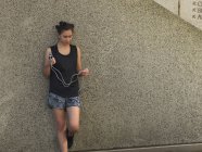 Giovane donna che tiene la corda di salto contro il muro di cemento — Foto stock