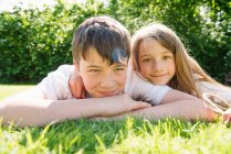 Portrait of brother and sister lying on grass — Stock Photo