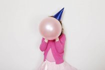 Chica sosteniendo globo rosa en frente de la cara - foto de stock