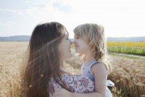 Mother and daughter in wheat field hugging — Stock Photo