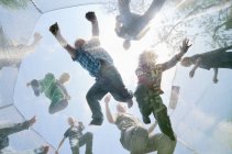 Mature men and boys jumping on trampoline, low angle view — Stock Photo