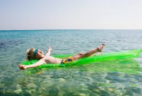 Menino novo em uma balsa inflável que relaxa na água do mar — Fotografia de Stock