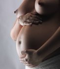 Pregnant woman supporting tummy — Stock Photo