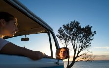 Junge Frau blickt in der Abenddämmerung aus dem Fenster eines Wohnmobils — Stockfoto