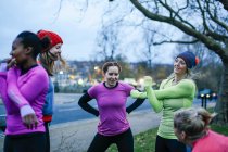 П'ять жінок дорослих бігунів, що прогріваються на межі міста в сутінках — стокове фото