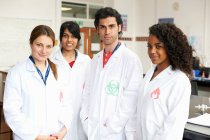 Portrait of four college students wearing lab coats — Stock Photo